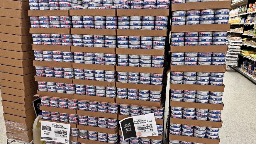 A giant stack display of canned tuna at the grocery store.